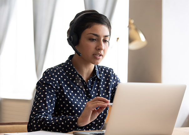 Advance Care Planning Specialist talking with headset looking at laptop 