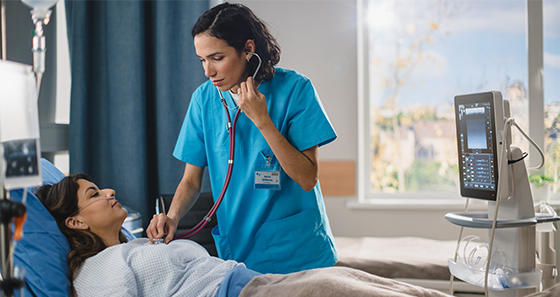 female patient in hospital bed female medical professional checking heart with a stethescope