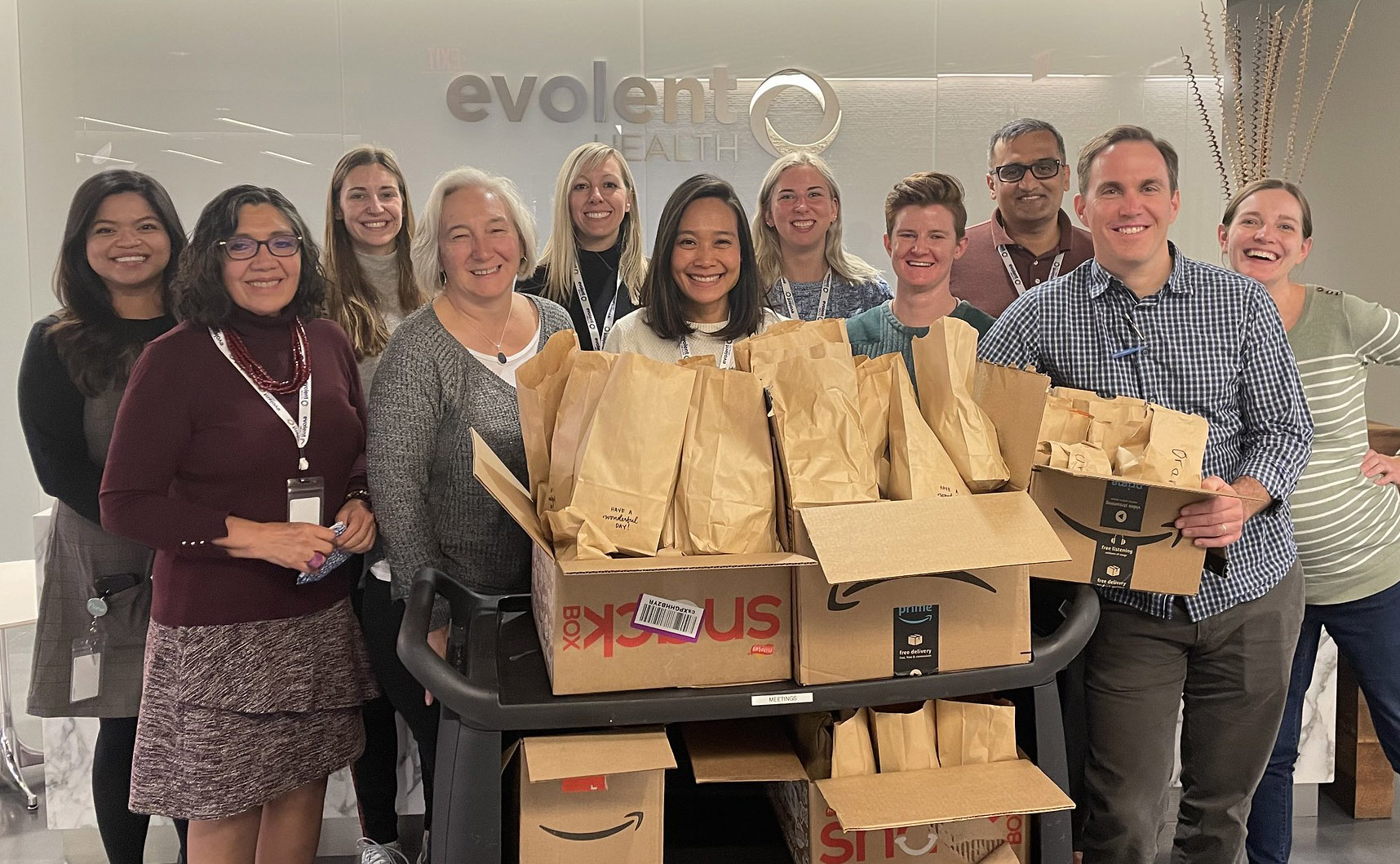 group of employees with brown bags and boxes at a community event 