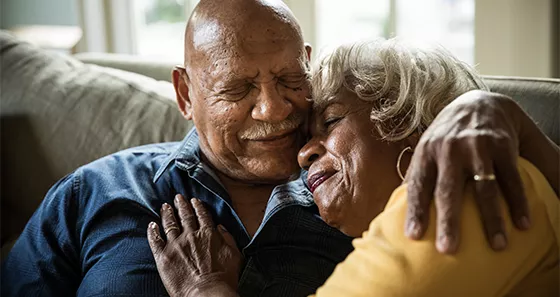 Older Hispanic Couple Embracing on couch and smiling