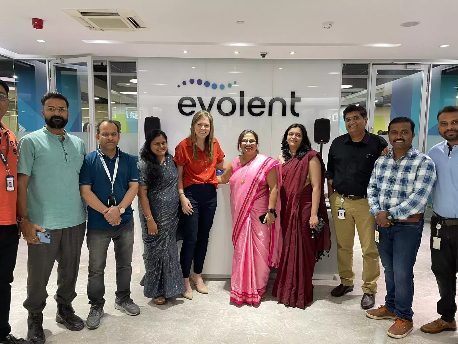 Row of employees in Pune, India with Evolent logo on the wall behind them 